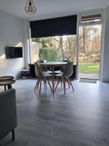 een eetkamer met een tafel en stoelen en een raam bij Natuurhuisje in Otterlo