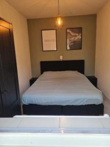 een kleine slaapkamer met een bed met een witte sprei bij Natuurhuisje in Otterlo +8 foto's