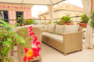 a wicker couch sitting on a patio with an umbrella at The Acropolis House of Flowers~Private Roof Garden in Athens