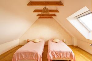 two beds in a attic room with a window at Ty Jane Dour - Maison avec jardin in Plouhinec