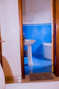 uma casa de banho em azulejos azuis com um lavatório e uma banheira em Nyumbani Hostel em Kigali