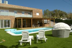 eine Gruppe von Stühlen und ein Pool vor einem Haus in der Unterkunft Villa Paraíso, exclusiva, todas las comodidades in Girona