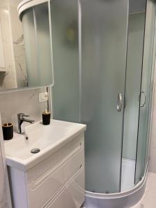 ein Bad mit einer Dusche und einem weißen Waschbecken in der Unterkunft Уникальная квартира в жк Амир in Almaty