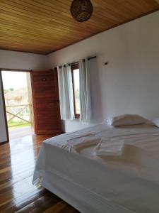 1 dormitorio con cama blanca y techo de madera en Sun Beach Chalés, en Luís Correia