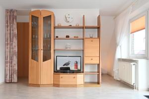 um centro de entretenimento em madeira com uma televisão numa sala de estar em Bernstein Mare-Comfort Wohnung 7 em Büsum