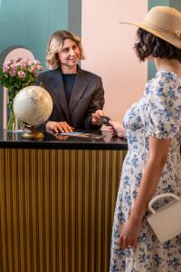 Eine Frau, die mit einer Frau hinter einem Tresen steht. in der Unterkunft Quatrum Napoli - B&B in Neapel