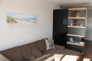 ein Wohnzimmer mit Sofa und Bücherregal in der Unterkunft Ferienwohnung E725 für 2-4 Personen an der Ostsee in Brasilien