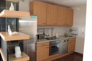 eine Küche mit Holzschränken und einem Kühlschrank aus Edelstahl in der Unterkunft Ferienwohnung E725 für 2-4 Personen an der Ostsee in Brasilien