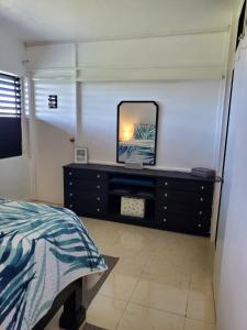 um quarto com uma cama e uma cómoda com um espelho em the Blue Ackee em Montego Bay