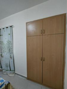 Zimmer mit einem Holzschrank und einem Vorhang in der Unterkunft TWO BEDROOM VACATION HOME AT SHARJAH DUBAI BOARDER BY MAUON.COM in Schardscha