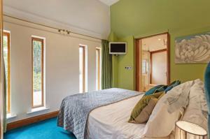 a bedroom with a bed with green walls and windows at Byford Lodge Luxury self-catering in Louth in Louth