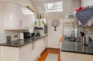 a kitchen with white cabinets and black counter tops at Byford Lodge Luxury self-catering in Louth in Louth