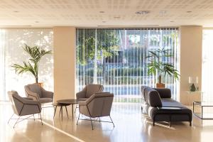 vestíbulo con sillas, mesas y ventanas grandes en Daniya Alicante, en Alicante