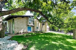 ein Haus mit einem grünen Garten mit einem Baum in der Unterkunft Beautiful Mid-Century Modern Lakehouse in Austin