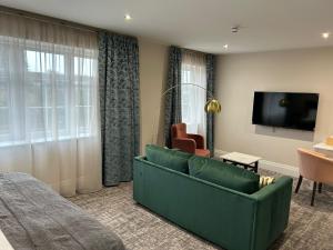 a living room with a green couch and a television at The Hillbrook Hotel & Spa - Sherborne in Sherborne