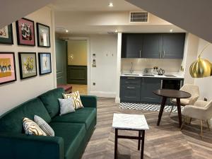 a living room with a green couch and a kitchen at The Hillbrook Hotel & Spa - Sherborne in Sherborne