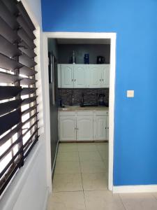 une cuisine avec des placards blancs et un mur bleu dans l'établissement the Blue Ackee, à Montego Bay