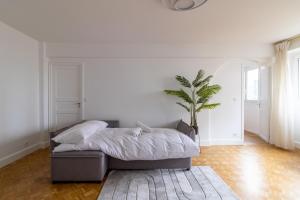a white bedroom with a bed and a potted plant at Comfortable apartment with view - Welkeys in Puteaux