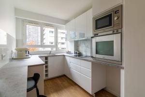 une cuisine avec des placards blancs, un four micro-ondes et une télévision dans l'établissement Comfortable apartment with view - Welkeys, à Puteaux