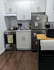 a kitchen with white cabinets and a stove and a sink at Modern One Bedroom in Union Sq - great location in New York