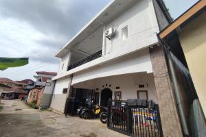 a white building with a motorcycle parked outside of it at Wisma Hiro Pertiwi in Palembang