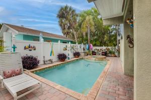 a swimming pool with a bench and a house at 1 Min walk to Beach with Pool, Spa, and Elevator in Holmes Beach