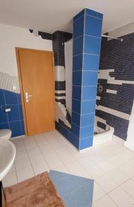W łazience znajduje się umywalka i prysznic z niebieskimi kafelkami. w obiekcie Gästehaus Da Fabio w mieście Bad Bocklet