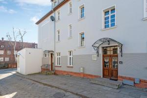 een groot wit gebouw met een houten deur bij Dom & House - Apartment Sea Of Mint in Sopot