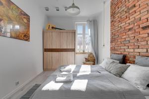 een slaapkamer met een groot bed met een bakstenen muur bij Dom & House - Apartment Sea Of Mint in Sopot