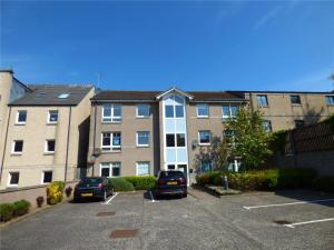 an apartment complex with cars parked in a parking lot at Spacious Elegant 2-BR Apartment in Aberdeen City Centre in Aberdeen