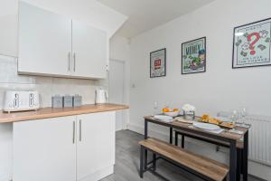 a kitchen with white cabinets and a table with food on it at STAYZED N2 - Modern, Colourful NG7 Home, Next To City Centre, Lots Of Amenities, Ideal for Long & Short Stays. in Nottingham