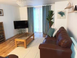 a living room with a brown leather couch and a coffee table at Spacious Elegant 2-BR Apartment in Aberdeen City Centre in Aberdeen