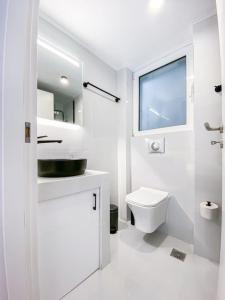 a white bathroom with a toilet and a window at Syntagma square, 60sqm Platinum suite in Athens