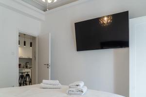 a white bedroom with a flat screen tv on the wall at Syntagma square, 60sqm Platinum suite in Athens