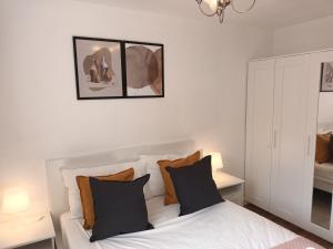 Spacious Elegant 2-BR Apartment in Aberdeen City Centre في أبردين: غرفة نوم مع سرير أبيض مع وسائد سوداء و برتقالية