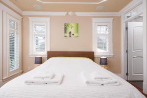 a bedroom with a large white bed with two towels at Oakridge Luxury Homestay in Vancouver