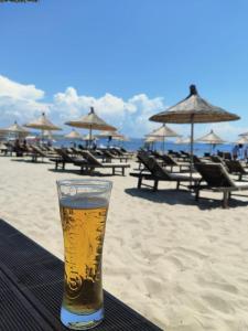 a glass of beer sitting on a table on the beach at COSMO Beach Hotel in Durrës
