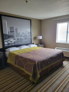 1 dormitorio con 1 cama grande y pantalla grande en Super 8 by Wyndham Aurora/Naperville Area, en Aurora
