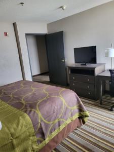 a hotel room with a bed and a desk and a television at Super 8 by Wyndham Aurora/Naperville Area in Aurora