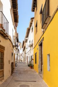 un callejón en un casco antiguo con edificios amarillos y blancos en Casa Museo RAKKANA - En el Centro de Requena, en Requena