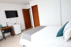 a bedroom with a bed and a desk with a television at Hotel Nattivo Uraba in Apartadó