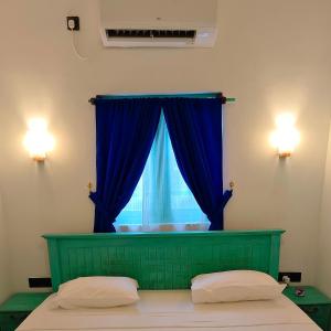 a bedroom with a bed with a blue curtain and a window at Mahi-Mahi Villa in Dickwella