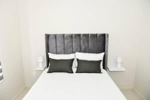 una camera da letto con un grande letto bianco con due cuscini di The Ellipse Palazzo Apartment a Midrand Altre 34 foto