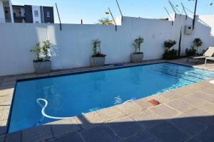 a large blue swimming pool with a white wall at The Mansioners Apartment in Midrand