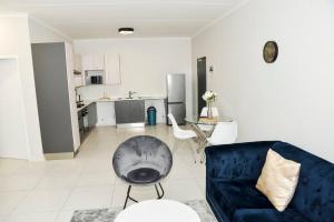 a living room with a blue couch and a kitchen at The Mansioners Apartment in Midrand