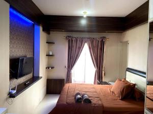 1 dormitorio con 1 cama, TV y ventana en Apt Sunter Park View Studio Murah with Pool & Wifi, en Yakarta