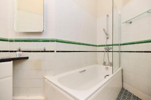 La salle de bains blanche est pourvue d'une baignoire et d'un lavabo. dans l'établissement The Cranley Gardens Escape - Spacious 2BDR Flat, à Palmers Green