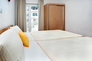two beds with white sheets and yellow pillows in a bedroom at Marko Apartmani in Rovinj