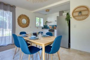 a kitchen and dining room with a wooden table and blue chairs at Résidence Escale Bleue in Andernos-les-Bains