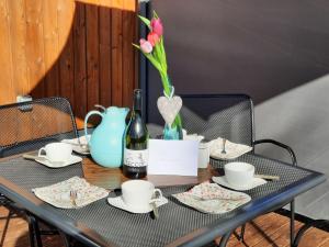 a table with a blue vase with flowers and a bottle of wine at Holiday Home Seeperle by Interhome in Wemding